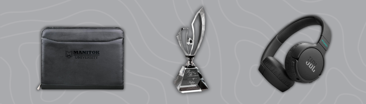 Leather padfolio with Manitou University logo, crystal award trophy, and JBL headphones on a gray background