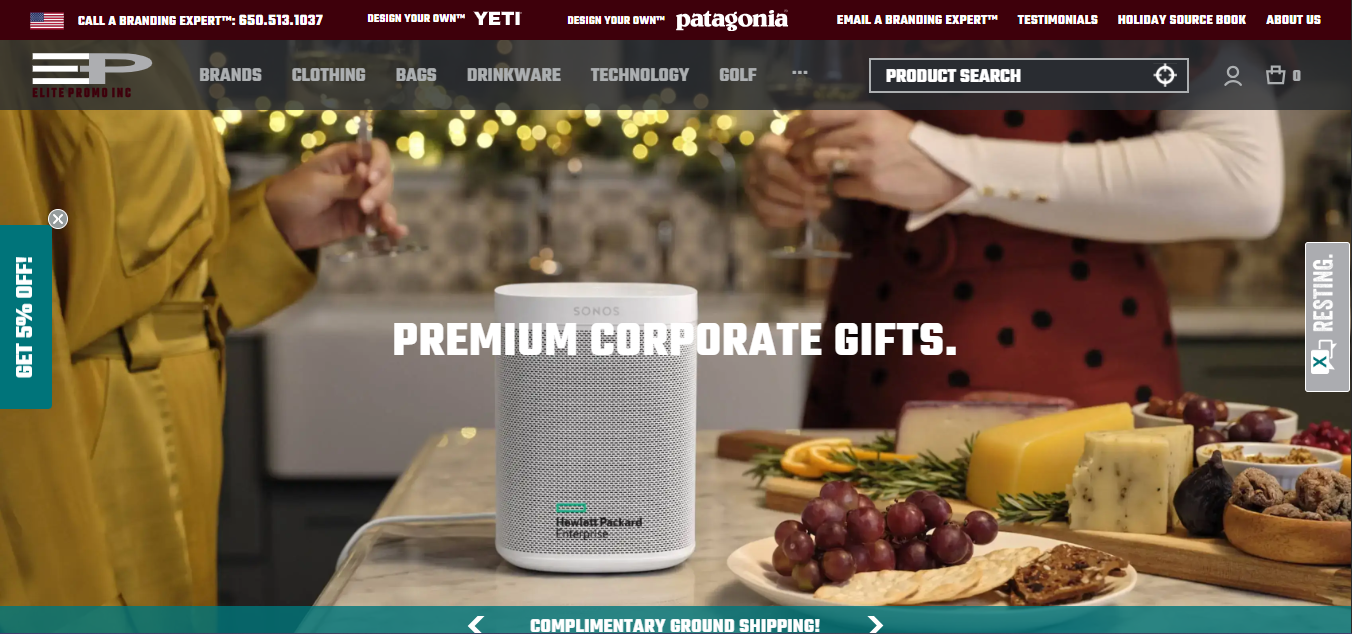 A Sonos speaker presented as a premium tech gift, placed on a table with cheese and fruit, while two people enjoy drinks in a festive kitchen setting.
