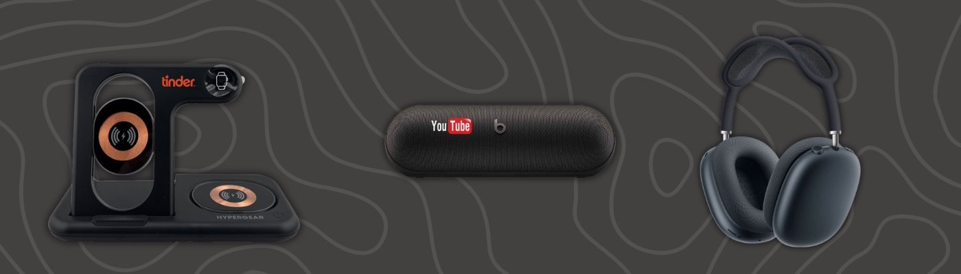 Tech gift set with HyperGear PowerFold 4-in-1 wireless charging stand, Beats Pill portable speaker, and Apple AirPods Max headphones on dark background, as part of new year corporate gifts.